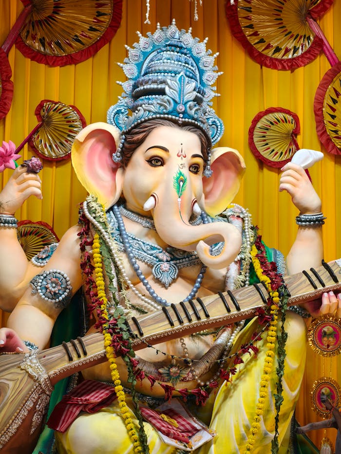 hero-contact Vibrant idol of Lord Ganesha adorned with traditional decorations and musical instrument.