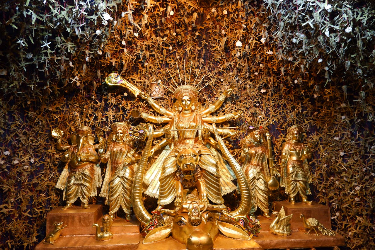 about-01 Intricately designed golden Durga idol with accompanying Hindu deities, symbolizing spirituality and worship.